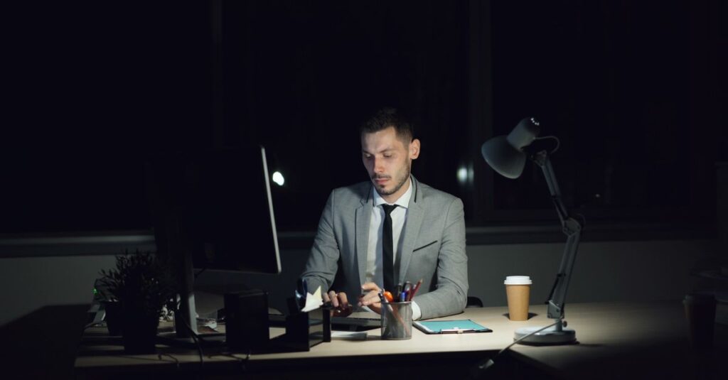 夜のオフィスで残業する社員